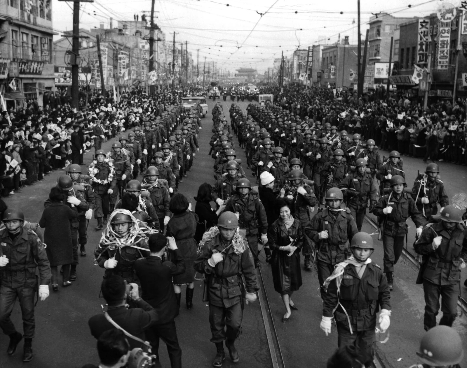 people and soldiers marching in the street