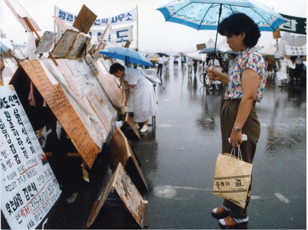 woman with umbrella looking at signs on the street