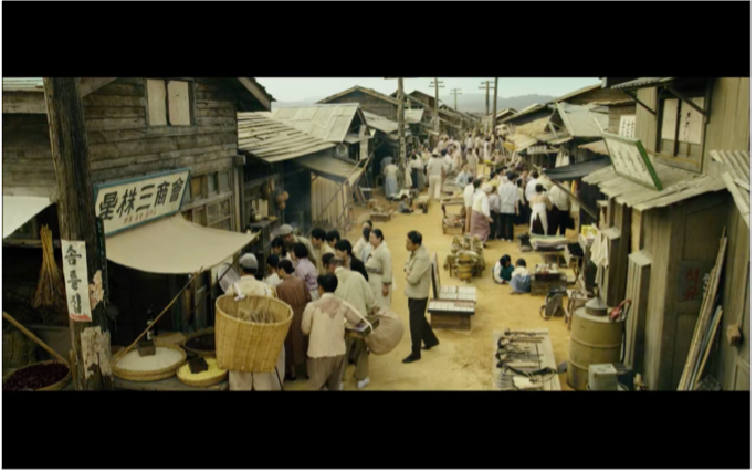 people gather around a radio in a narrow street