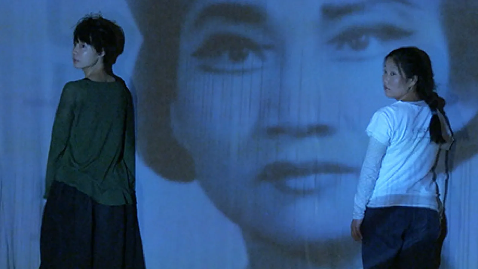 picture of two people in front with large woman's face in background from film