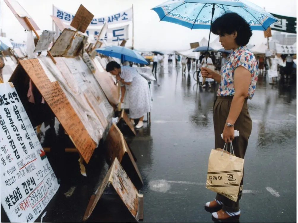 woman with umbrella looking at signs on the street